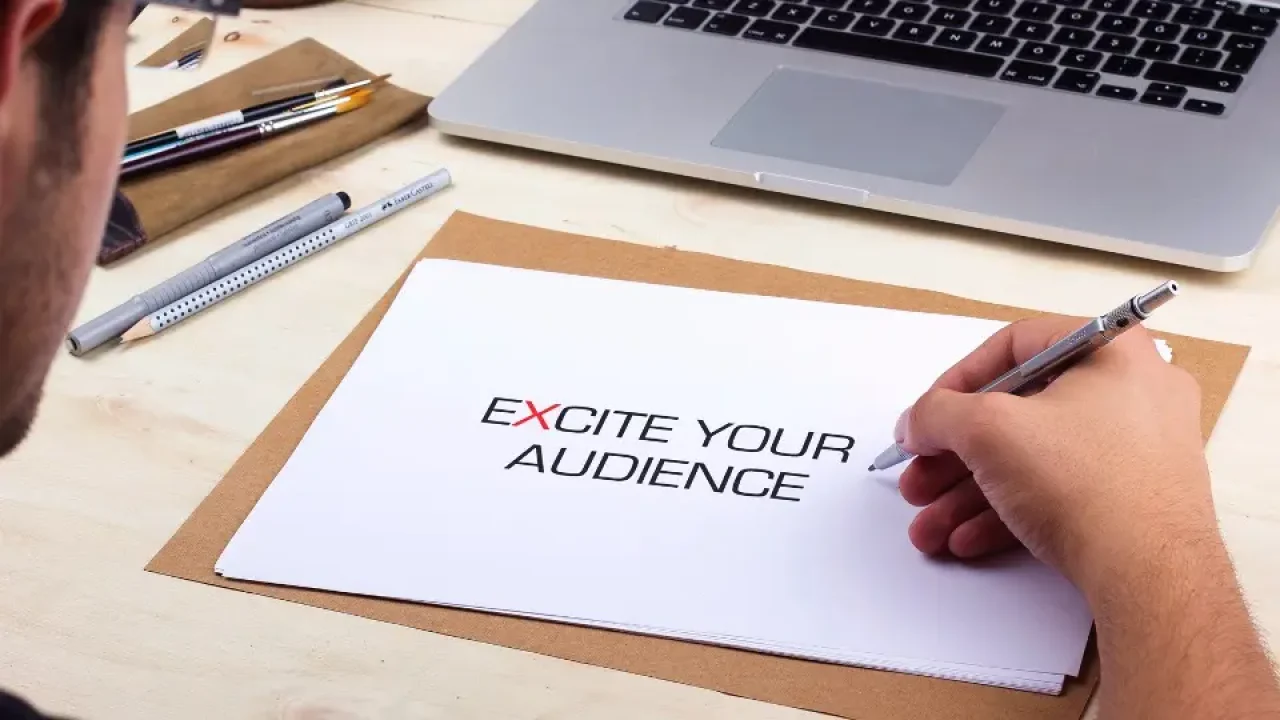 En person skriver "Excite your audience" på en lapp i RetailX sine logofarger